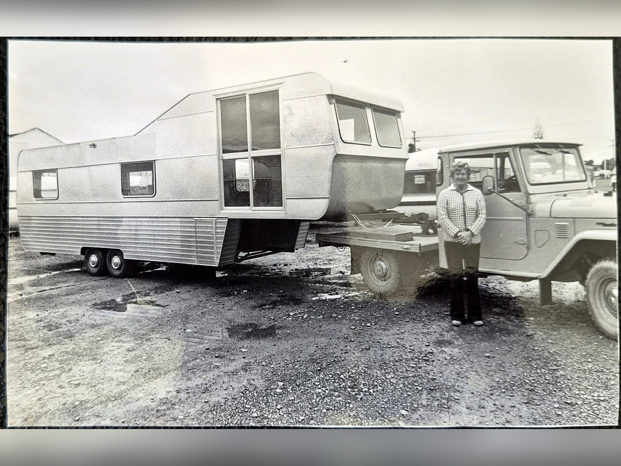 Large caravan with tow vehicle and a person alongside