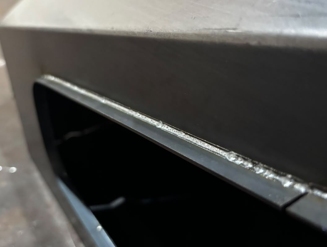 Close-up of laser welding along the edge of a trailer body opening